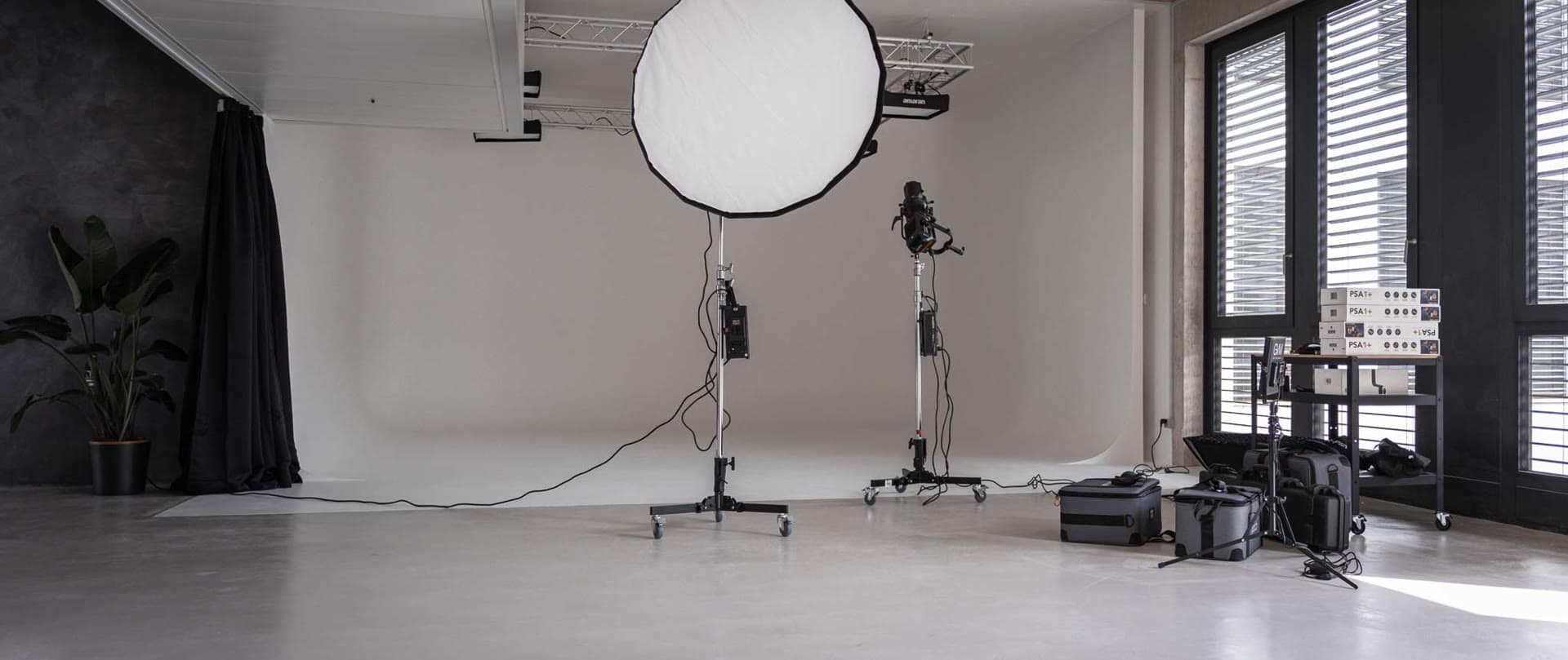 Studio photo avec parabolique, fenêtres en lumière du jour et fond noir