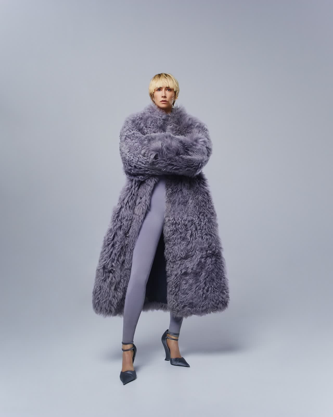 Full-length studio portrait in a long grey fur coat