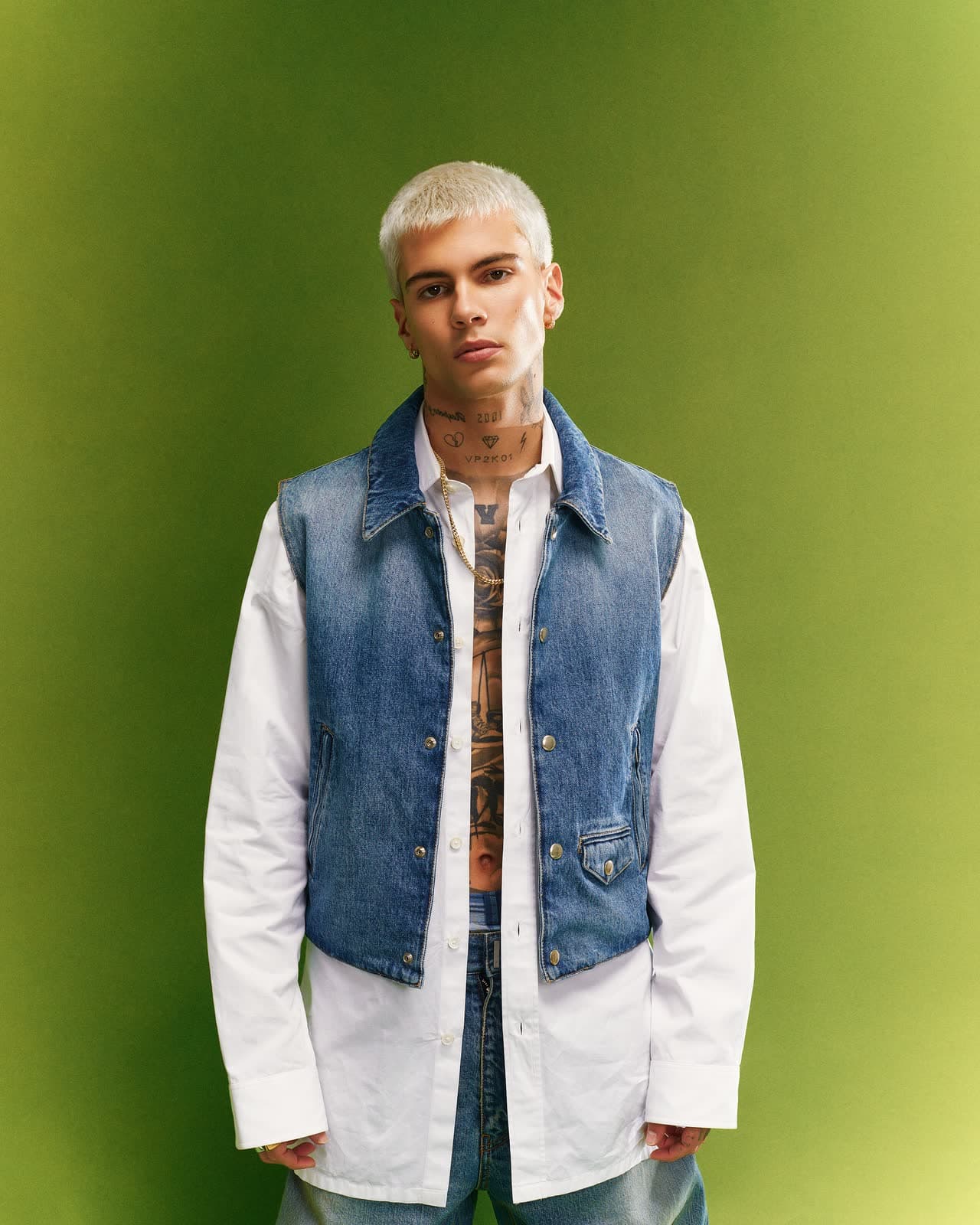 Studio portrait in a denim vest over a white shirt on a green gradient