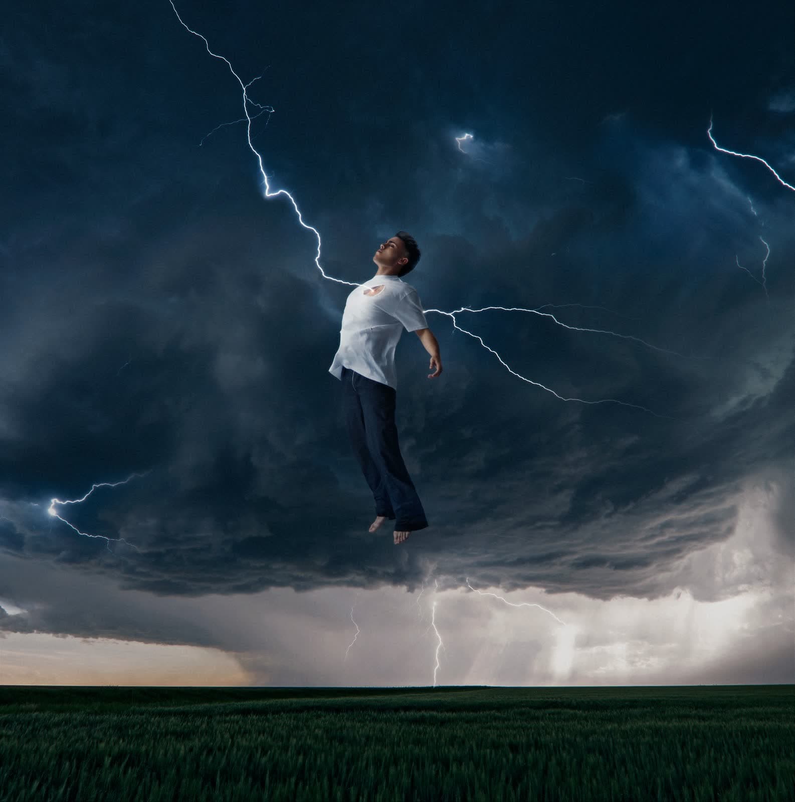 Composite: a figure floating above a field under lightning