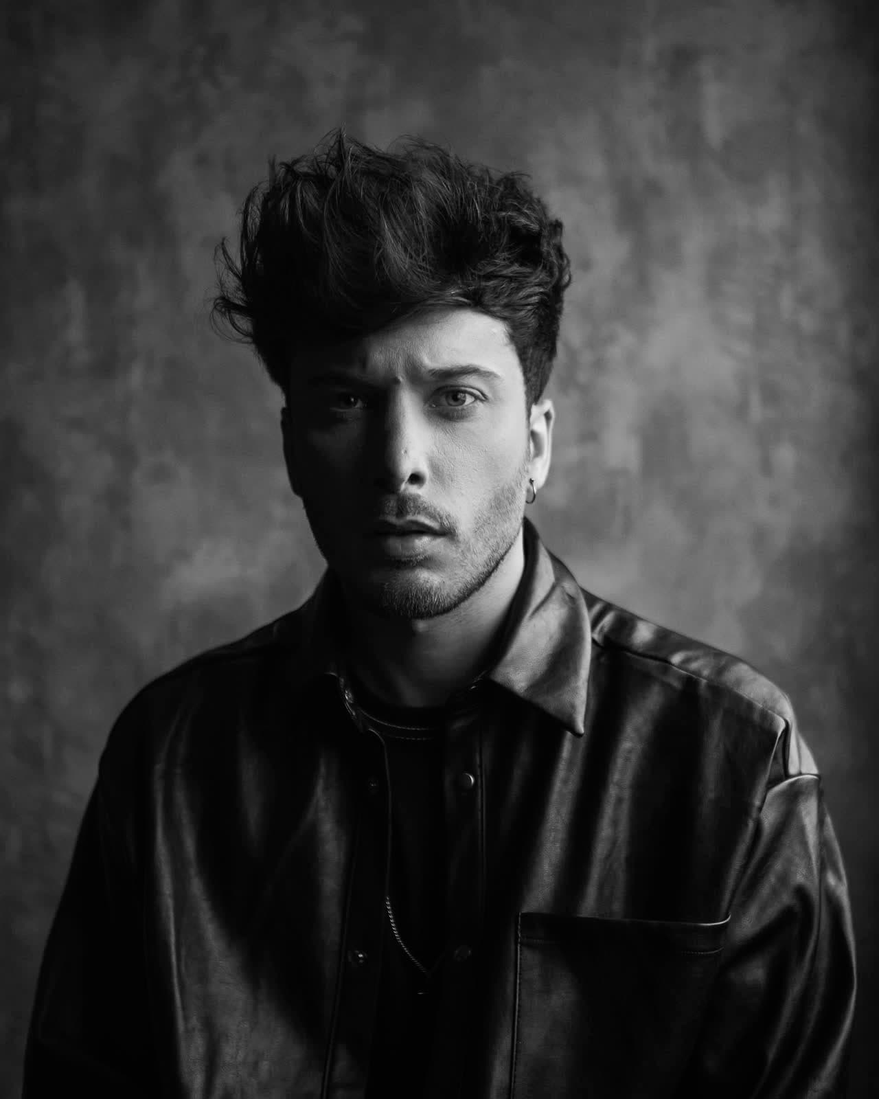 Black-and-white studio portrait against a painted backdrop