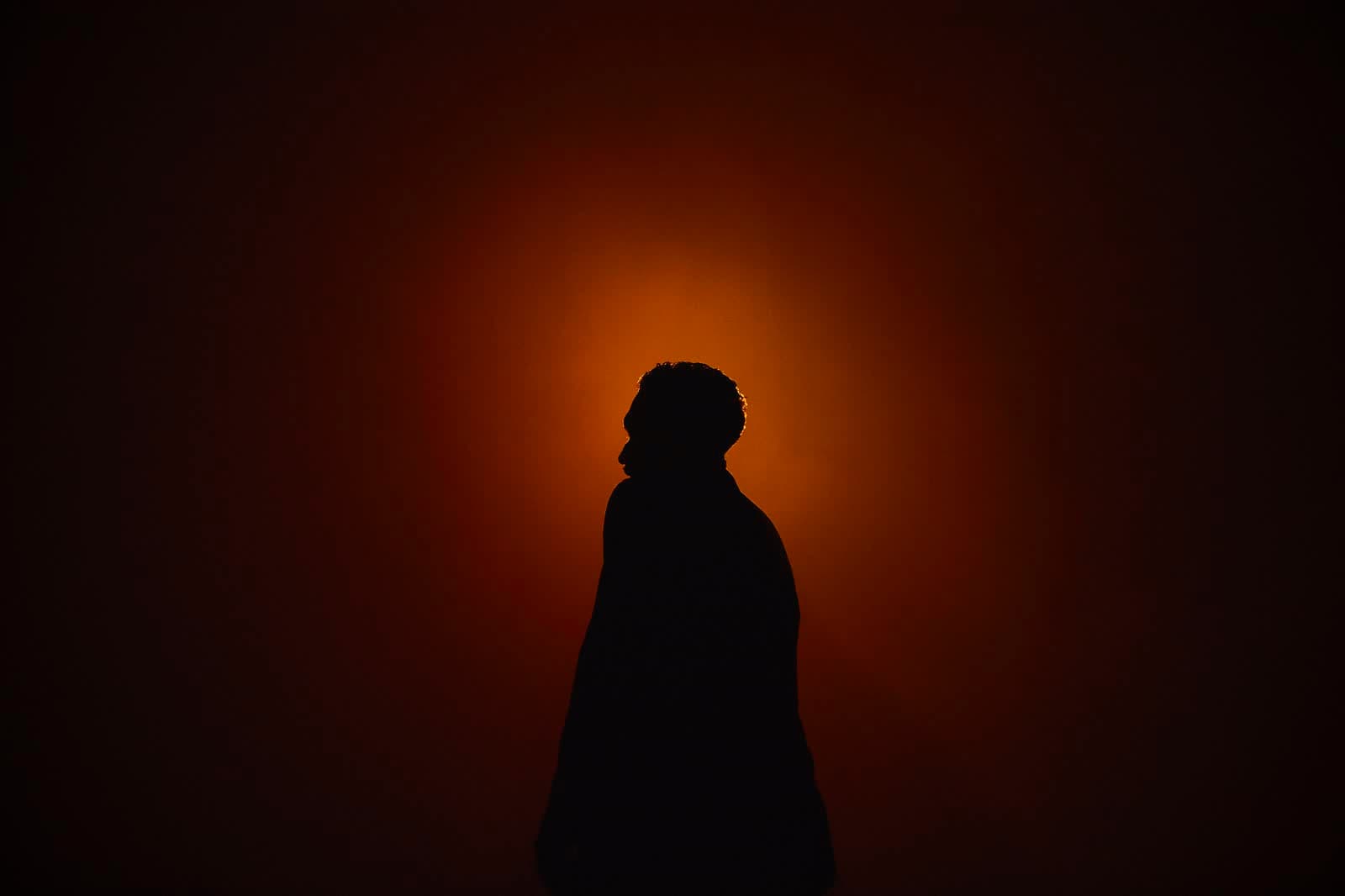A silhouette against an orange glow in stage haze