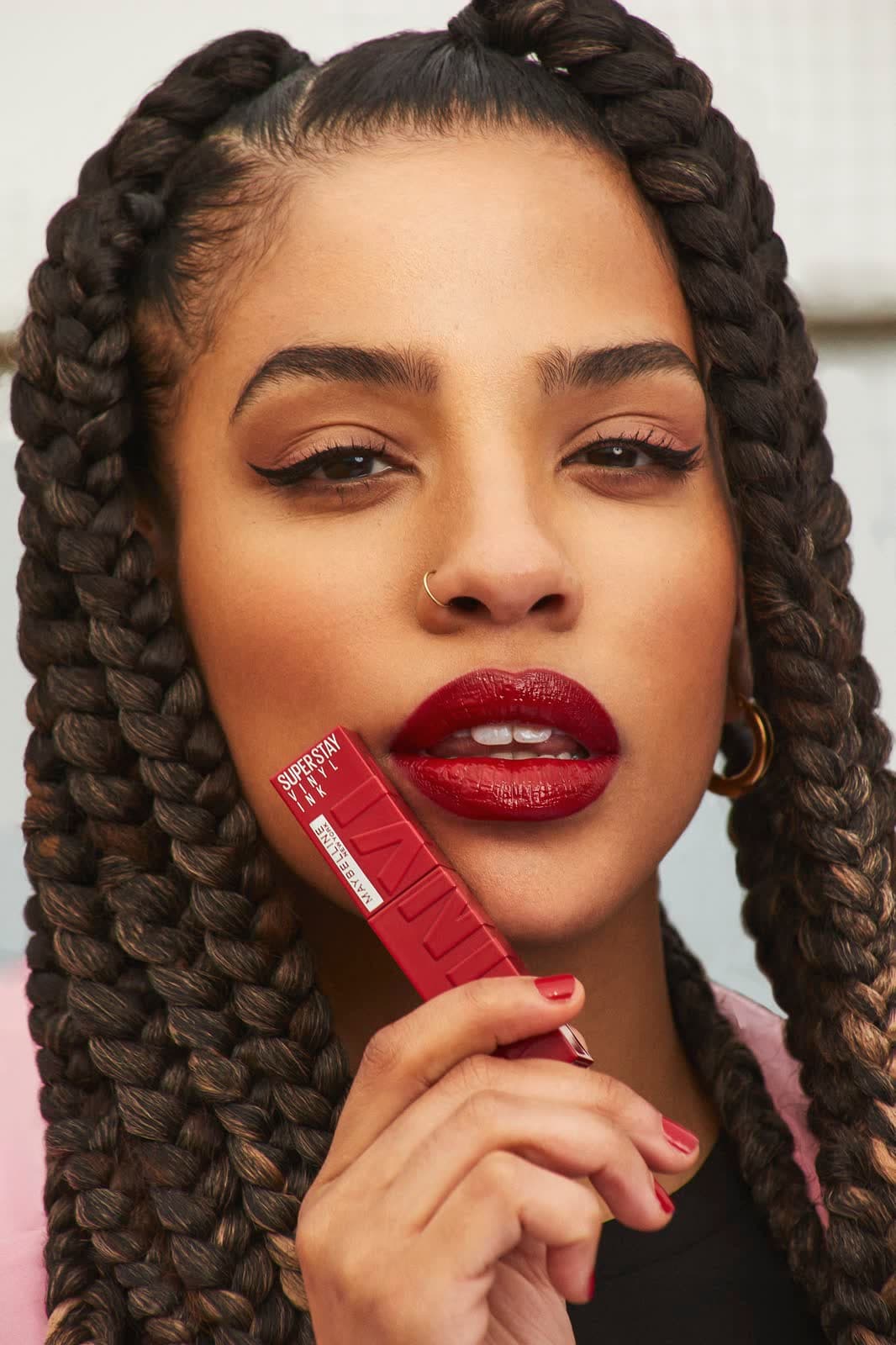 Campaign frame: model with braids holding a red lipstick