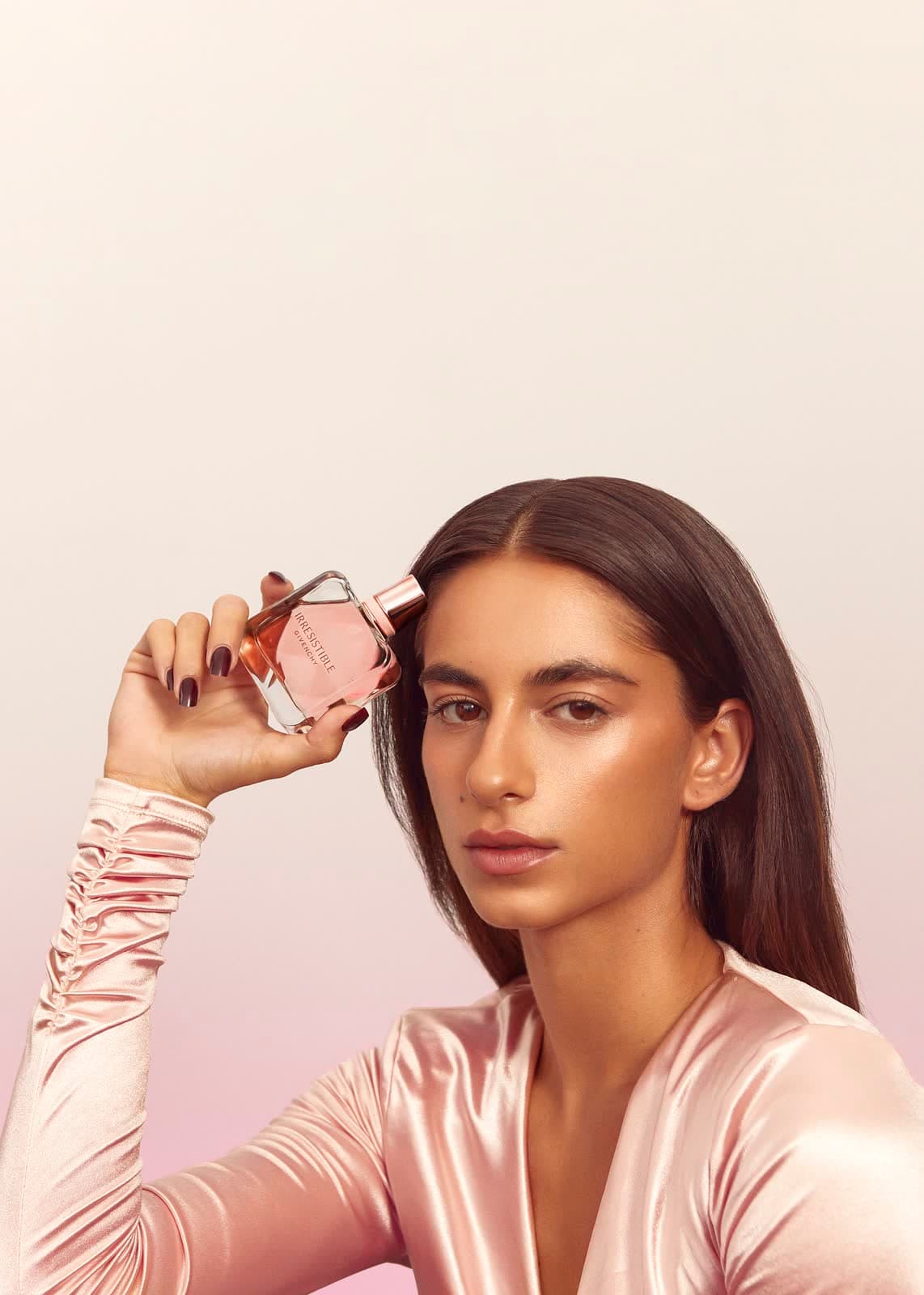 Campaign frame: a fragrance bottle held to the light in a satin sleeve