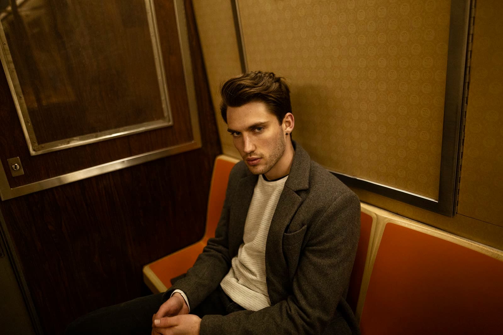 Man in a tailored jacket on a banquette in a warm-lit interior