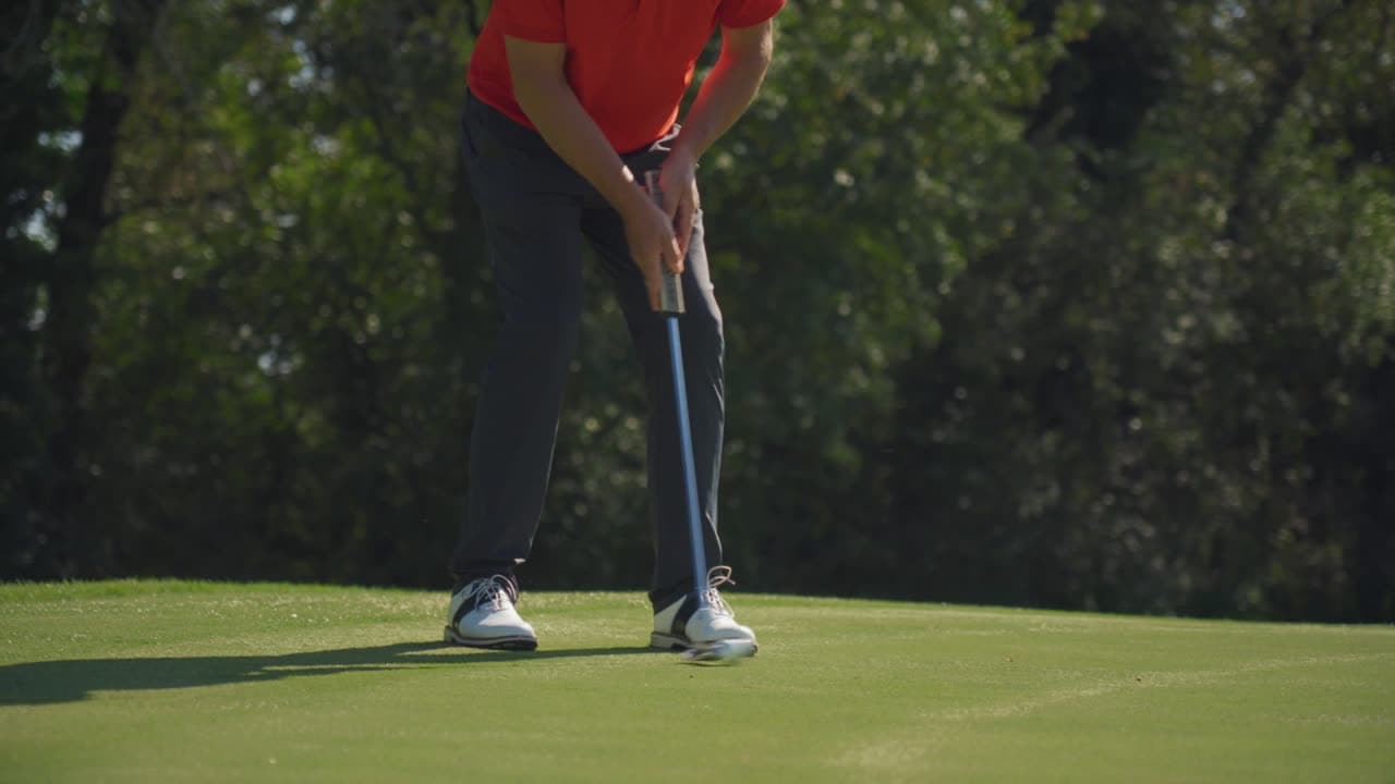 Un joueur au putting sur le green, polo rouge